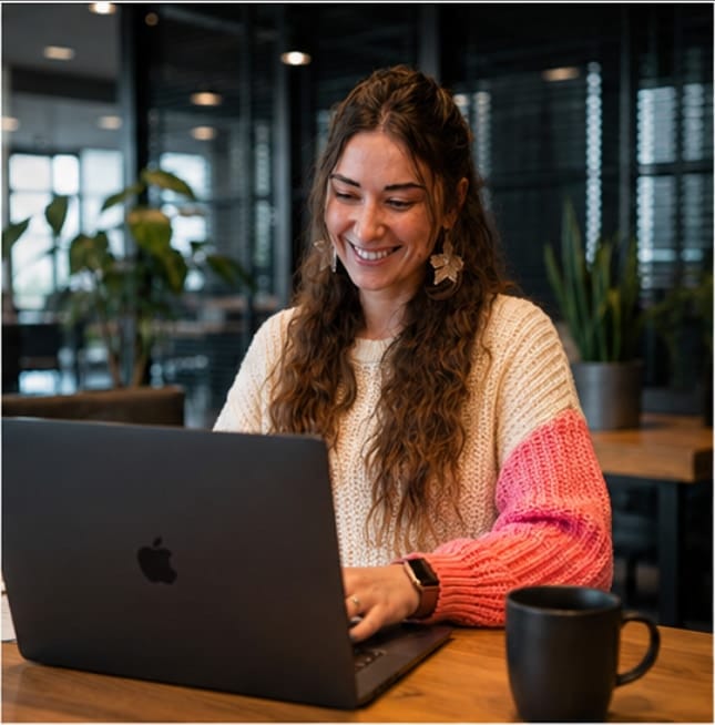 Nata van Houdt working on a laptop at a wooden table