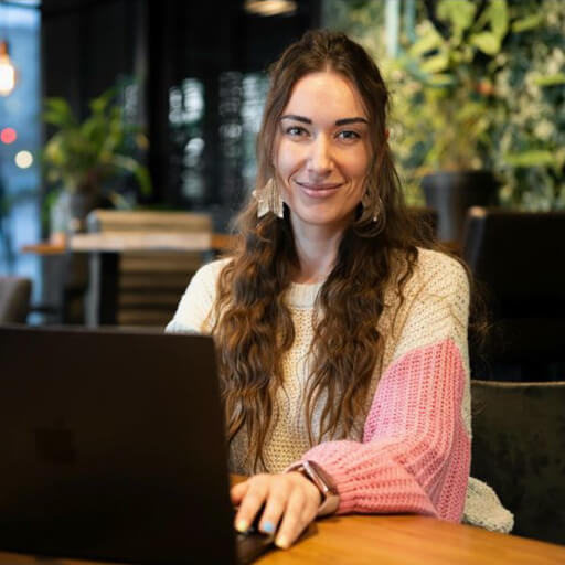 Nata van Houdt working on a laptop in a warmly lit café